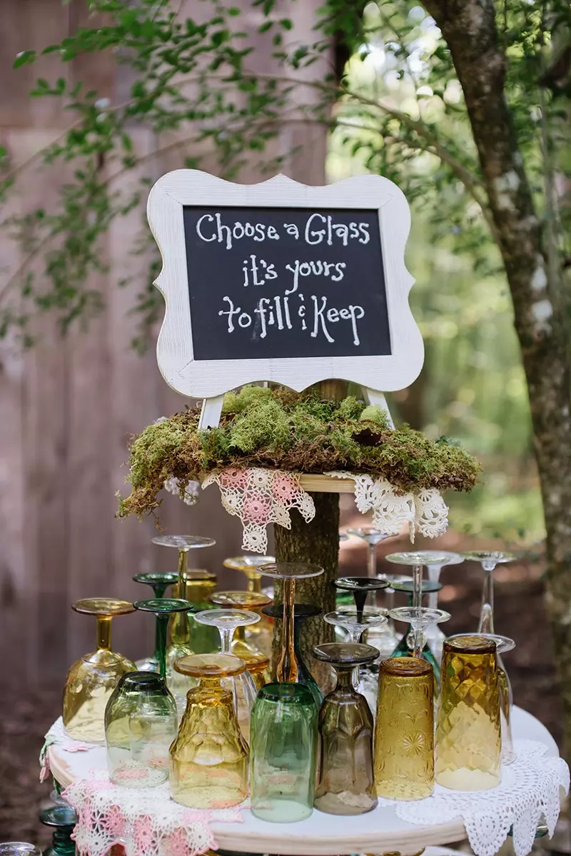 Table of glassware with sign in the woods.