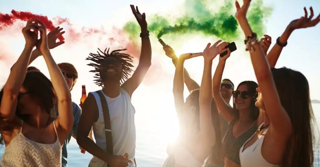picture of people partying at the beach with smoke sticks theme