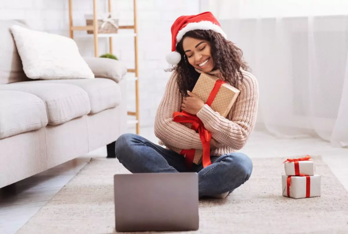 Virtual Christmas party ideas: woman hugging her gift while on a video call