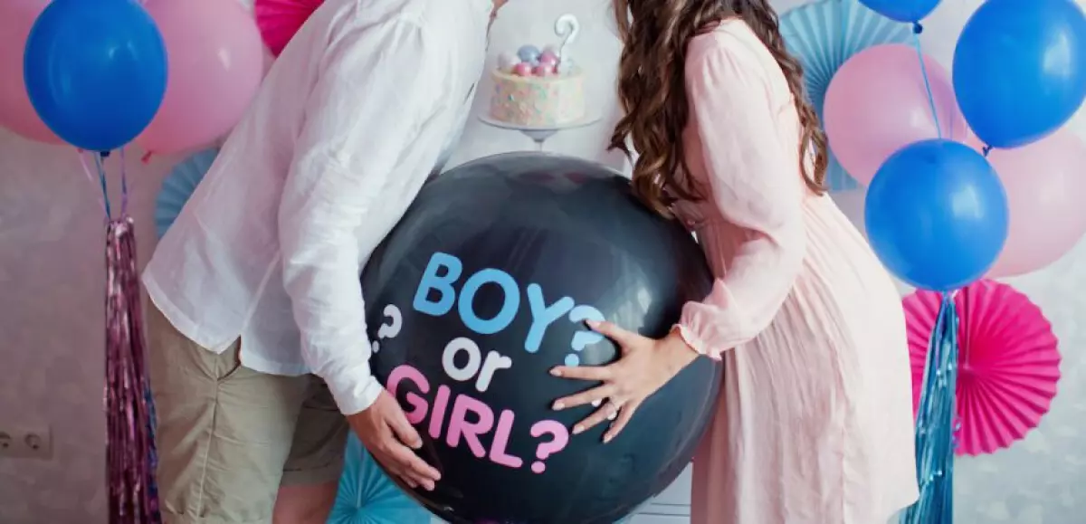 Gender reveal party: couple holding a gender reveal balloon
