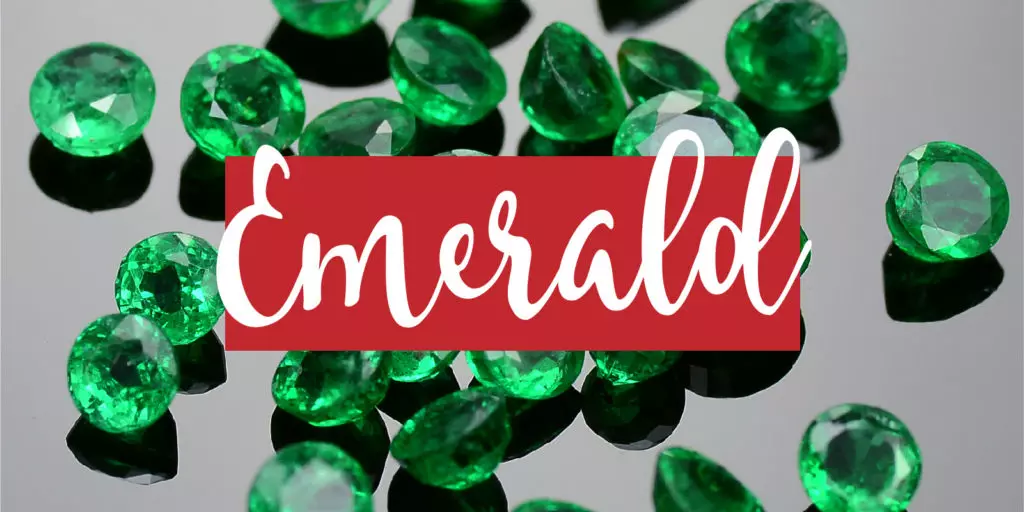 Featured image for the 20th anniversary gemstone gift theme of emerald, a close-up of a pile of cut emerald gemstones on a dark background with a text overlay that reads "emerald"